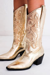 The boot of the season has arrived, and these metallic beauties are made for way more than just walking! The Danilo by Billini is a long western boot that gives the perfect touch of western inspired styling to your everyday, festival, or game day look!   If in between sizes, we recommend sizing up Heel height 7 cm Low stacked block heel Closed pointed toe Structured upper Western inspired embroidery Oversized side pull tabs for a pull on design Synthetic upper, lining and outsole