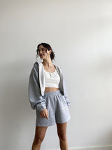 Tell it how it is with our Sleepy and Sleepy Embroidered Zip Up Hoodie! This relaxed fit, cropped hoodie is just made for lounging in, yet perfect for throwing on when you're running out the door. Made with the softest fleece fabric and complete with the sweetest yellow embroidery, this set is guaranteed to be a favorite all year long. Our Sleepy + Sleepy Embroidered Zip Up Hoodie is shown here with our Sleepy + Sleepy Embroidered Sweat Shorts.