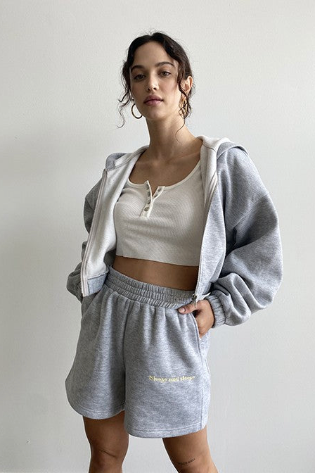 Tell it how it is with our Sleepy and Sleepy Embroidered Zip Up Hoodie! This relaxed fit, cropped hoodie is just made for lounging in, yet perfect for throwing on when you're running out the door. Made with the softest fleece fabric and complete with the sweetest yellow embroidery, this set is guaranteed to be a favorite all year long. Our Sleepy + Sleepy Embroidered Zip Up Hoodie is shown here with our Sleepy + Sleepy Embroidered Sweat Shorts.