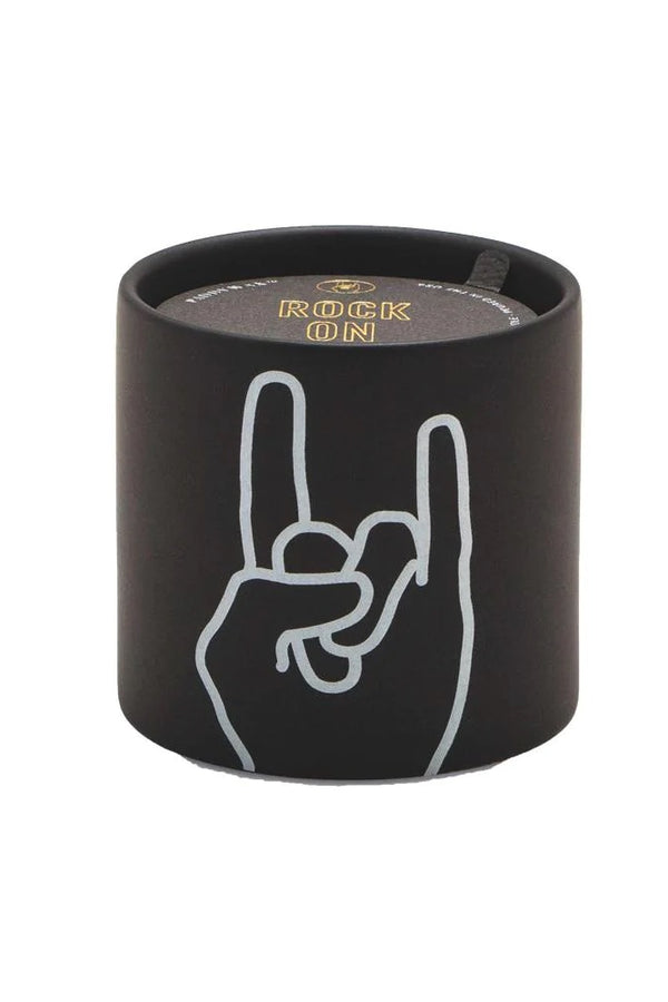 Rock on! Express yourself with these matte ceramic candles. Each candle comes with a gold foil stamped dust cover with a fun sentiment to share with the people you love.  *In Store Pickup Only* Top Notes: Pink Peppercorn, Bergamot, Clove Bud, Saffron Middle Notes: Black Leather, Gingerlily, Cedar Leaf, Elemi Resin Base Notes: Dark Oak, Agarwood, Guaiac, Burlwood, Cade Size: 5.75 oz. Vessel: Ceramic Dimensions: 3.125" L x 3.125 " W x 3 " H